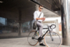 Man in business attire sitting on a bicycle while using his smartphone outside a modern building.