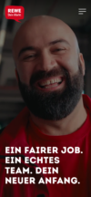 REWE Karriere-Startseite mit dem Porträt eines lächelnden Mitarbeiters im roten REWE-Outfit. Der Slogan lautet: „Ein fairer Job. Ein echtes Team. Dein neuer Anfang.“ im modernen Webdesign.