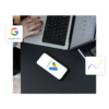 Arbeitsplatz-Szene aus der Vogelperspektive mit Laptop und einem Smartphone, das das Google Ads Logo zeigt. Ergänzt durch Overlays des Google Partner Badges und einer ansteigenden Performance-Grafik.