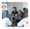 Inbound-Marketing-Agentur bei einem HubSpot-Strategie-Meeting im Konferenzraum, visuell untermauert durch Overlays des HubSpot Gold Partner Badges und des CRM-Logos.