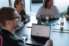 Meeting in der Digitalagentur mit Fokus auf das Thema Sichtbarkeit in der Google-Suche. Ein aufgeklapptes Macbook zeigt die Suchzeile von Google.