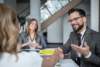 Geschäftsmann im Anzug schüttelt lächelnd einem Geschäftspartner die Hand während eines Meetings in einem modernen Büro; Symbolbild für professionelle B2B-Partnerschaften